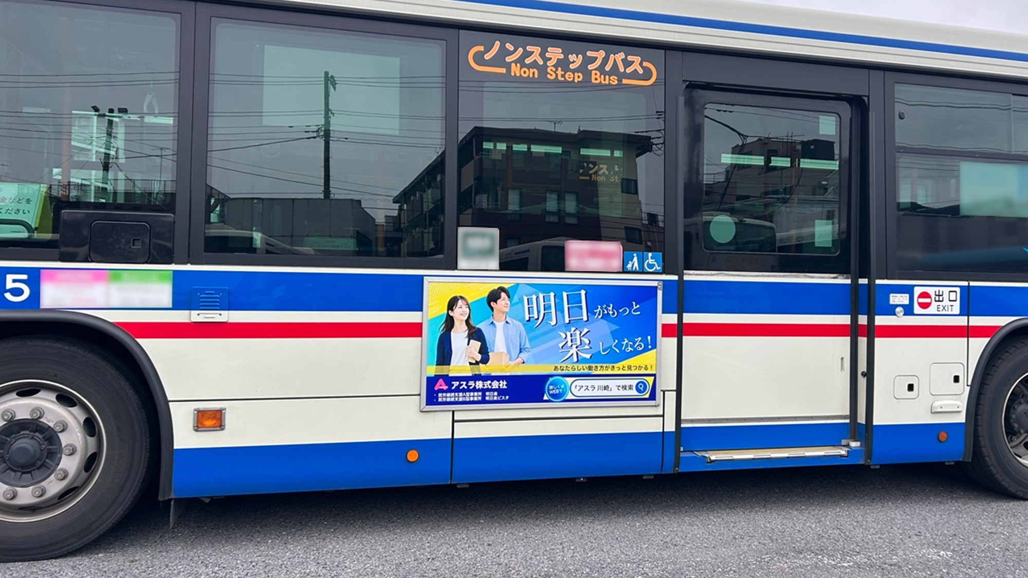 川崎鶴見臨港バスの車体全体と歩道側に掲出されたアスラ株式会社の車外広告