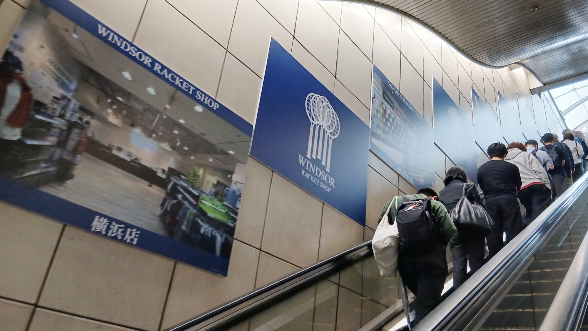 国際展示場駅のエスカレーター沿いでロゴと店舗写真を交互に掲出したウインザーラケットショップの広告